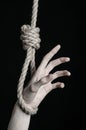 Suicide and depression topic: human hand hanging on rope loop on a black background Royalty Free Stock Photo