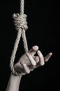 Suicide and depression topic: human hand hanging on rope loop on a black background Royalty Free Stock Photo