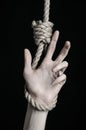 Suicide and depression topic: human hand hanging on rope loop on a black background Royalty Free Stock Photo