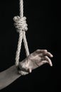 Suicide and depression topic: human hand hanging on rope loop on a black background Royalty Free Stock Photo