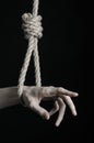 Suicide and depression topic: human hand hanging on rope loop on a black background Royalty Free Stock Photo
