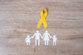 Suicide prevention and Childhood Cancer Awareness, Yellow Ribbon and family paper shape for supporting people living and illness. Royalty Free Stock Photo