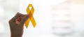 Suicide prevention and Childhood Cancer Awareness, Yellow Ribbon on wooden background for supporting people living and illness.