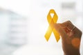 Suicide prevention and Childhood Cancer Awareness, Yellow Ribbon on wooden background for supporting people living and illness.