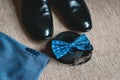 Suit, blue bow tie, leather black shoes and belt. Grooms wedding morning. Close up of modern man accessories