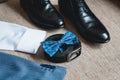Suit, blue bow tie, leather black shoes and belt. Grooms wedding morning. Close up of modern man accessories Royalty Free Stock Photo
