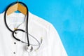 Suit Doctor's with a stethoscope on a hanger. Doctor's coat on a blue background. Ad space, copyspace, medical template