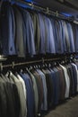 Suit jackets in hanger in men fashion and apparel store. Row of many clothes in rack or wardrobe. Royalty Free Stock Photo