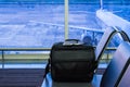 Suitcase in airport departure lounge, airplane in background, summer vacation concept Royalty Free Stock Photo