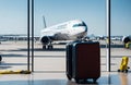 suitcase in the airport departure lounge, airplane in the blurred background Royalty Free Stock Photo