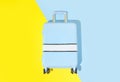 Suitcase on a blue yellow background with long deep shadows. Travel concept