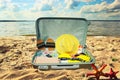 Suitcase with clothes and different things for trip lying closeup on the sand beach in summertime