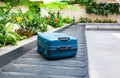 suitcase on a conveyor belt surrounded by green tropical plants in a baggage claim area at the airport Royalty Free Stock Photo