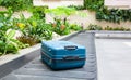 suitcase on a conveyor belt surrounded by green tropical plants in a baggage claim area at the airport travel background Royalty Free Stock Photo