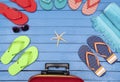 Suitcase with flip-flops, beach towel and sunglasses on wooden table. Royalty Free Stock Photo