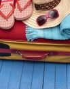 Suitcase with flip-flops, beach towel and sunglasses on wooden table. Royalty Free Stock Photo