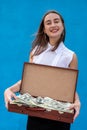 Suitcase full of money is in female hands, isolated on blue Royalty Free Stock Photo