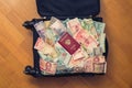 Suitcase full money of south-east Asia with russian passport and American hundred dollar bill. Royalty Free Stock Photo