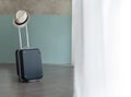 Suitcase with male hat on pastel blue and bare wall