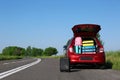 Suitcase near family car with open trunk full of luggage on highway. Space for Royalty Free Stock Photo