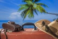 Suitcase, sun hat, photo camera and sunglasses with sea water, coconut palm tree and blue sky background on sunny summer day in Royalty Free Stock Photo