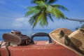 Suitcase, sun hat, photo camera and sunglasses with sea water, coconut palm tree and blue sky background on sunny summer day in Royalty Free Stock Photo