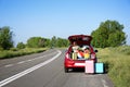 Suitcases near family car with open trunk full of luggage on highway Royalty Free Stock Photo