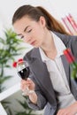 suited young lady looking into gladd red wine Royalty Free Stock Photo