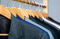 Suits for men hanging on the rack. Mens suits in different colors hanging on hanger in a retail clothes store, close-up Royalty Free Stock Photo
