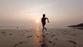 Sukabumi October 10 2023, a small Asian child is running on the beach towards the beautiful sparkling sunset