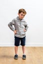 Sulking conflicted boy standing with hands on hips expressing attitude Royalty Free Stock Photo