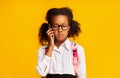 Sulky Black Schoolgirl Talking On Phone With Parents In Studio