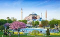 Sultanahmet district in Istanbul, Turkey. Walking people, green grass fields and fountain near famous landmark Hagia Sophia.