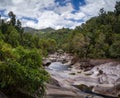 A dried-up small river flows along the rocky bottom from behind the horizon in the center of the frame. Surrounded by tropical Royalty Free Stock Photo