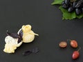 Suluguni cheese with ricotto is located on a black stone plate, next to grape berries and a bunch of ripe grapes on a leaf. Black Royalty Free Stock Photo