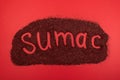 Sumac spice on red surface. Inscription Sumac of Dried ground powder. Design element. Delicious Oriental spices