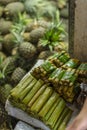 Suman or budbud, a rice cake wrapped in banana leaves, for sale in a public market in Tagaytay. A pile of pineapples nearby Royalty Free Stock Photo