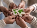 Summary A diverse group collaboratively raises an Earth-themed puzzle piece in a casual setting, possibly symbolizing Royalty Free Stock Photo