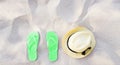 Summer accessories on beach texture banner background. Green Flip flops and hat on sand top view. Slippers shoes and vacation Royalty Free Stock Photo