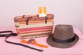 Summer accessories - straw beach bag, sun hat, belt, watch, suntan lotion, orange denim shorts on pink wooden table Royalty Free Stock Photo