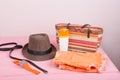 Summer accessories - straw beach bag, sun hat, belt, watch, suntan lotion, orange denim shorts on pink wooden table Royalty Free Stock Photo