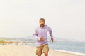 Summer active sports concept. Attractive happy young African-American man hipster in sport hoody running on the beach. Royalty Free Stock Photo