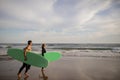 Summer Activities. Happy Young Couple Carrying Surfboards Walking Along Shoreline Royalty Free Stock Photo