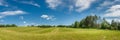 summer agricultural landscape. panoramic view of a hilly field under a blue cloudy sky