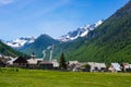 Summer in the Alps, tourist resort, vacation village. Blooming alpine meadow and lush green woodland set amid high altitude mounta Royalty Free Stock Photo