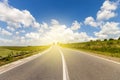 Summer asphalt road in sunrise to the sun. Beautiful yellow field with sun flare effect countryside landscape Royalty Free Stock Photo