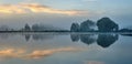 Summer-autumn landscape of trees reflected in the water of the lake on the shore and the sky in the early foggy morning. Panoramic Royalty Free Stock Photo