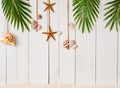 Summer background with beach sand, starfish coconut leaves, and shell decoration hanging on wooden background Royalty Free Stock Photo