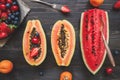Summer background. Fresh juicy berries, watermelon and papaya on the black wooden table, top view