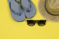 Summer background. Straw sun hat, sunglasses and beach striped flip flops on a yellow background. Royalty Free Stock Photo